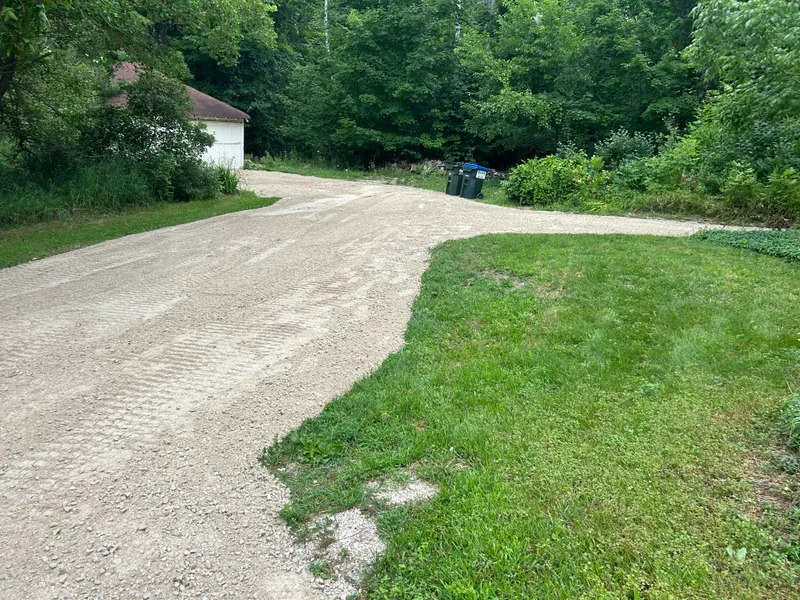 Gravel driveway curving past a white garage