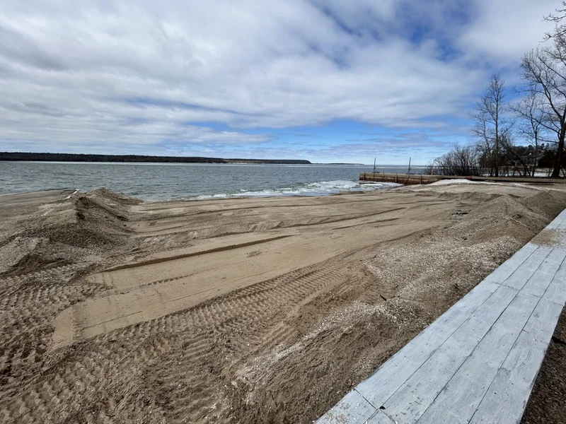 Freshly graded sand with fresh tracks beside a lake and boardwalk