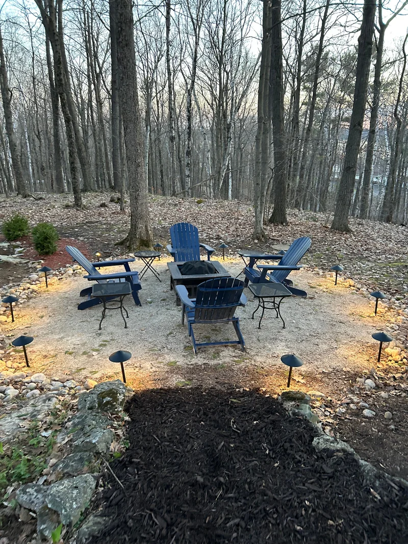 Fire pit seating area with low path lights in a wooded yard