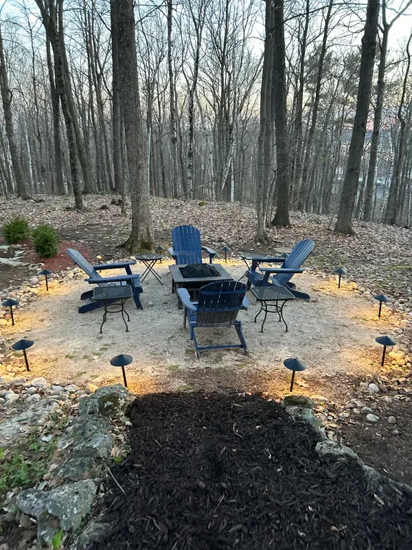 Fire pit seating with path lights in a wooded yard
