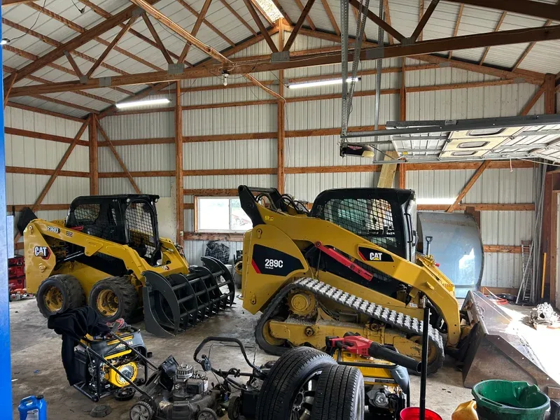 Two Cat skid steers stored in an equipment shop