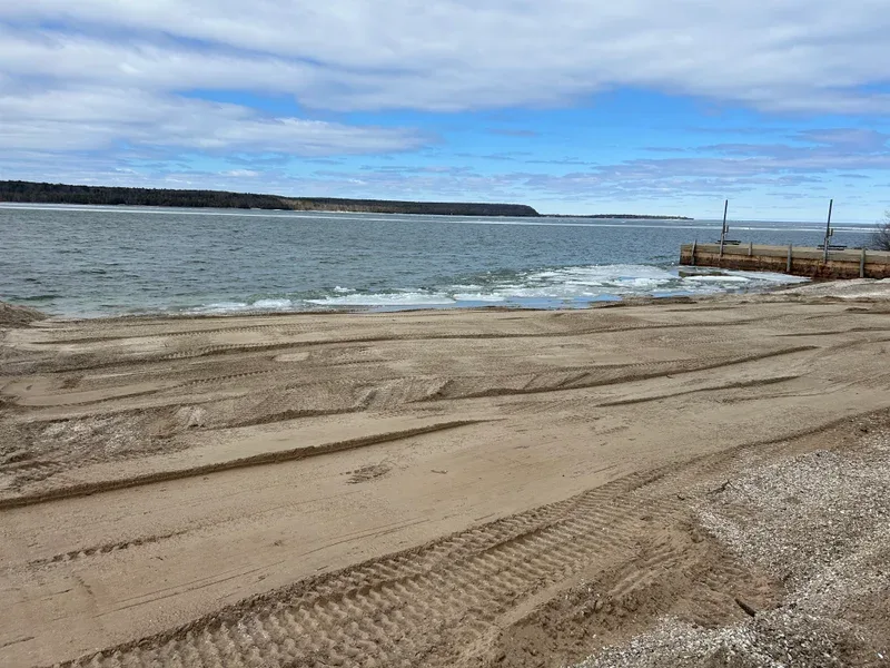 Graded sand with tire tracks leading toward a dock