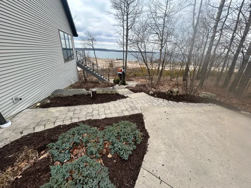 Stone pathway and steps with mulched beds beside a lakeside home